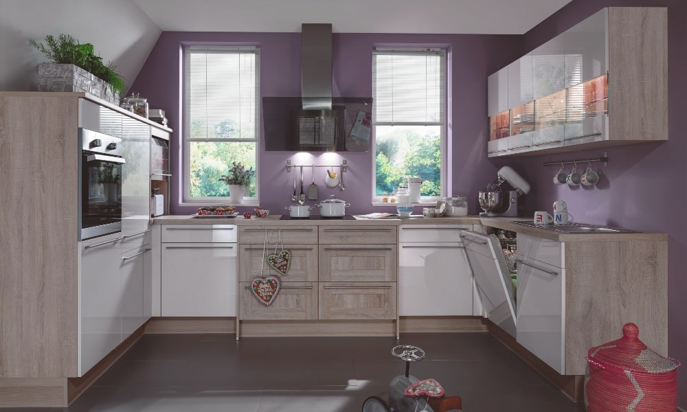 Cocina CORIANDRE, con armarios de cocina en blanco brillo y madera, y una campana extractora decorativa para ganar espacio a la pared. mobiliario rincon con luz integrada para aprovechar esquina cocina